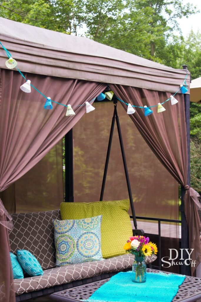 Cozy outdoor swing with birdie garland above and decorative throw pillows