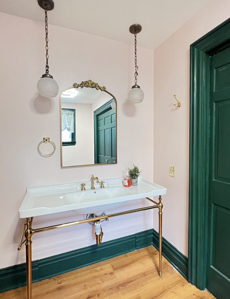 blush bathroom with green trim and gold fixtures