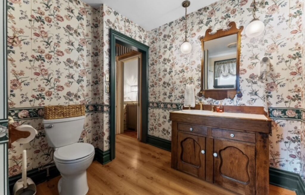 outdated bathroom with peeling wallpaper and worn fixtures