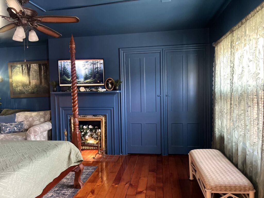 moody blue bedroom makeover with painted walls, wood floors, bench seating and soft natural light through curtains